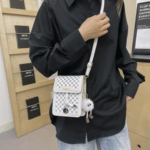 White textured leather crossbody bag featuring gold logo and cute plush doll pendant