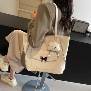 Detail of cream tote bag with black butterfly clasp and white cloud plush charm