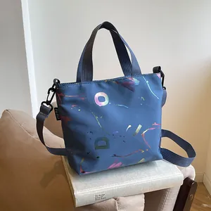 Detail of blue waterproof nylon crossbody bag featuring colorful laser-effect patterns