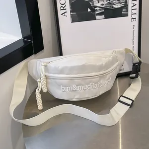 Macro detail of white nylon chest bag with 3D embroidery and woven zipper pullers