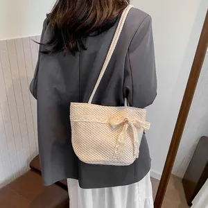 Detalle de este bolso tejido a mano crema con lazo de encaje y texturas de ganchillo fino