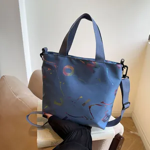 Detail of blue nylon crossbody bag with colorful artistic graffiti and woven handles