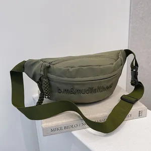 Gros plan sur le sac bandoulière vert olive avec broderie et détails de sangle en nylon