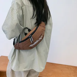 Rear view of model wearing a brown crossbody bag with adjustable black strap and white logo