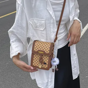 Detail of vintage patterned crossbody bag featuring a plush charm and fashion label