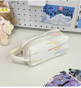Detailopname van witte clutch met textuur, kleurrijk borduursel en handige ritssluiting