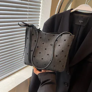 Detail van grijze visgraat emmertas met zwarte polkadots en decoratieve strik