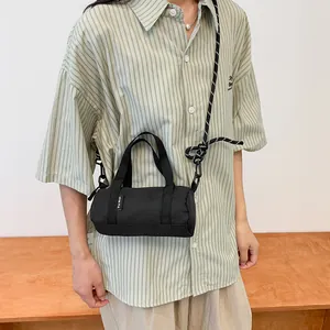 Close-up of mini black cylinder crossbody bag made of durable canvas with rope shoulder strap
