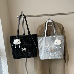 Detail of crinkled tote bags with silver butterfly buckle and plush cloud charm