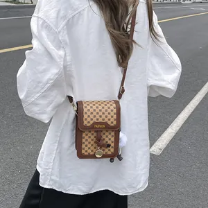 Detailed view of a brown vintage patterned crossbody bag with fashion metal plate and charm