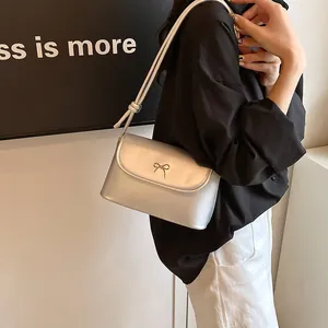 Elegante silberne Schultertasche mit goldener Schleife am Model im urbanen Stil