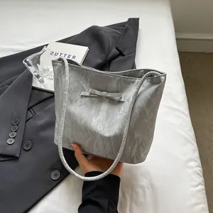 Détail du sac cabas texture marbre argenté avec nœud en soie et doubles poignées
