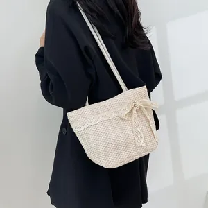 Detalle de bolso de paja tejido a mano con adorno de encaje blanco y lazo para playa