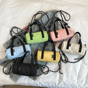 Mini cylindrical oxford cloth crossbody bags in vibrant colors on a blue denim jacket