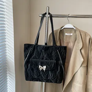 Detail of black tote bag featuring wrinkled texture and silver butterfly buckle