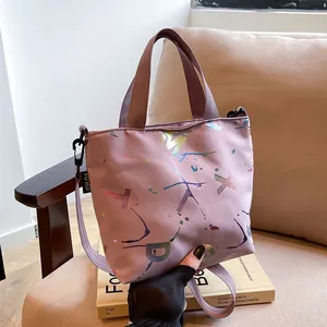 Close-up of pink nylon crossbody bag with colorful splash letters on an English book