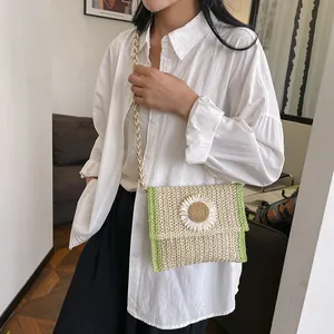 Detail of woven straw bag with white daisy flower and green trim on a shoulder strap