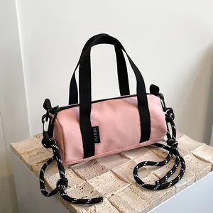 Detailed shot of pink nylon cylinder mini bag with woven rope strap on stone surface
