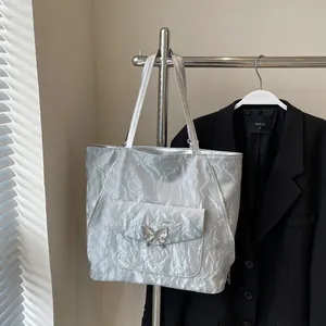 Detailed macro view of silver metallic pleated tote bag with butterfly metal buckle