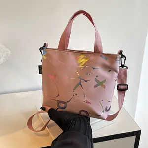 Close-up of pink nylon tote bag featuring colorful laser-cut letters and woven labels