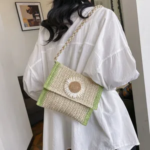 Detail of straw woven crossbody bag with green trim and a large white daisy flower
