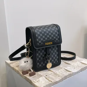 Detail of crossbody bag with geometric pattern, fashion text and plush monster charm