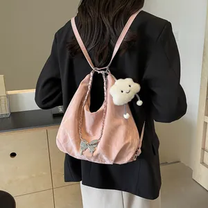 Pink tote bag with butterfly pendant and plush cloud charm worn as a stylish backpack
