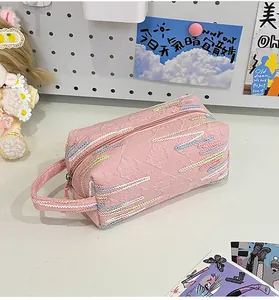 Detail van roze gewatteerde clutch met meerkleurig borduursel en geweven handvat