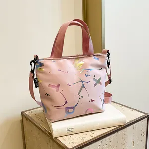 Detail of pink nylon tote with laser alphabet prints and adjustable shoulder strap