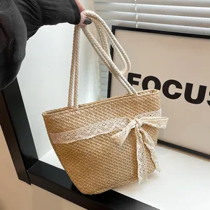 Detalle de bolsa de paja tejida a mano con lazo de encaje blanco y asa de cuerda