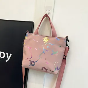 Detail view of pink nylon crossbody bag featuring colorful letter prints and woven handles