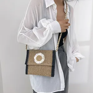 Detail of straw woven crossbody bag with white daisy flower and braided rope strap