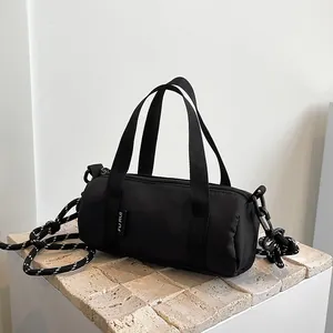 Mini black cylindrical nylon crossbody bag featuring woven rope strap and zipper closure