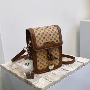 Detail of vintage brown leather bag with floral textile and plush monster charm