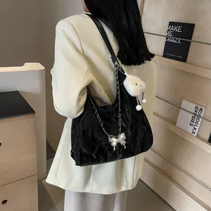 Detail of black pleated texture shoulder bag with butterfly chain and plush charm