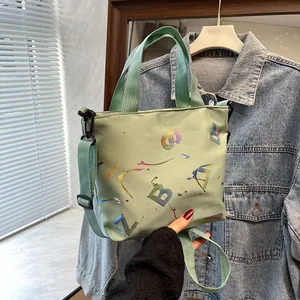 Close-up of light green nylon tote bag with colorful graffiti lettering and adjustable strap