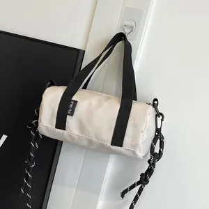 Close-up of beige mini cylinder bag showing glossy nylon fabric and rope shoulder strap