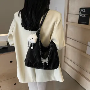 Detail of black wrinkled PU leather tote bag with silver chain and butterfly pendant