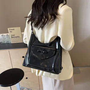 Detailweergave van de zwarte laklederen shopper met strikdetail over de schouder gedragen