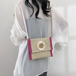 Detail of straw woven crossbody bag with white daisy flower and rose red stitching