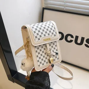 Detail of a creamy white mini crossbody bag with geometric prints and a plush eye charm