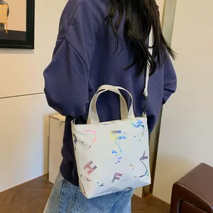 White graffiti canvas crossbody bag with colorful lettering worn by a model