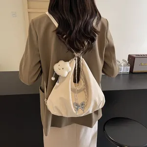 Detail of cream backpack with chain strap, butterfly charm and plush cloud accessory