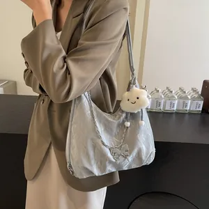 Detail of silver metallic hobo bag with delicate metal chain and plush cloud charm