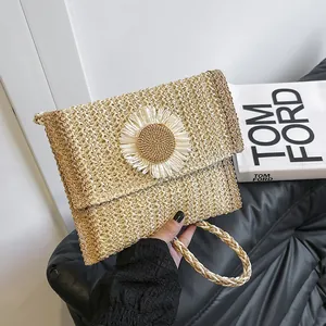 Detail of hand-woven straw shoulder bag featuring a large white daisy flower ornament