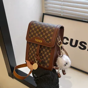 Detail of brown vintage crossbody bag with gold floral patterns and plush charm decoration