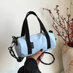 Detail view of mini cylinder crossbody bag in light blue with textured woven strap
