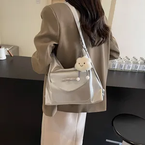 Detail van zilveren hobo-tas met strikaccent en witte pluche wolkhanger aan de schouderriem