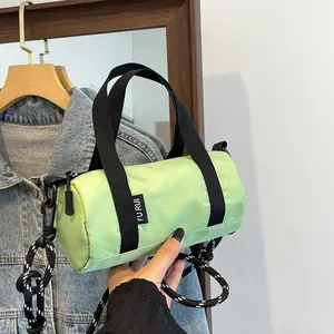 Detailed view of mini green cylinder cross-body bag with woven rope shoulder strap
