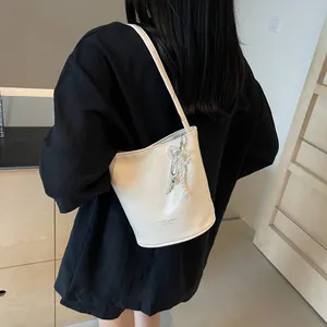 Detail of white bucket bag with pearl bow charm and Fashion & Bags text on smooth PU leather